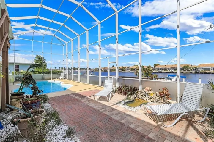 View of pool with a lanai, a sunroom, patio surround, and a water view