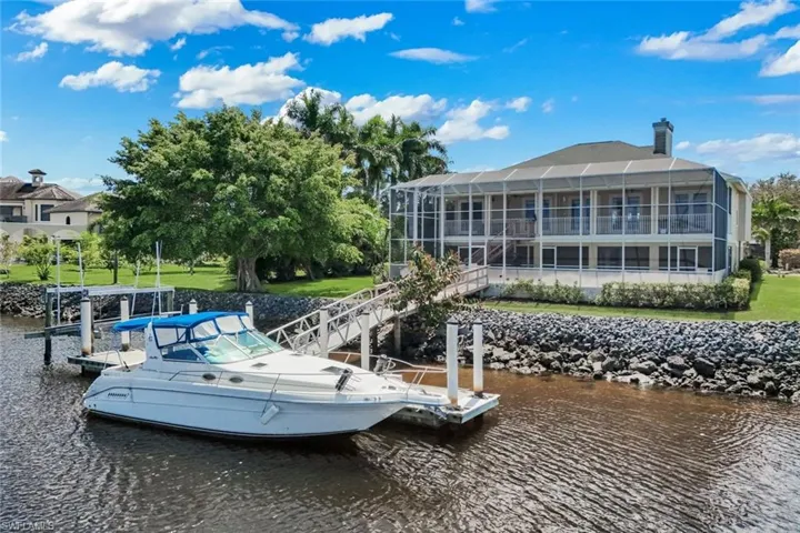 Dock area with a water view, a yard, and a sunroom