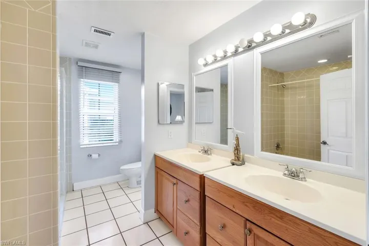 Full bathroom with double vanity and light tile patterned flooring