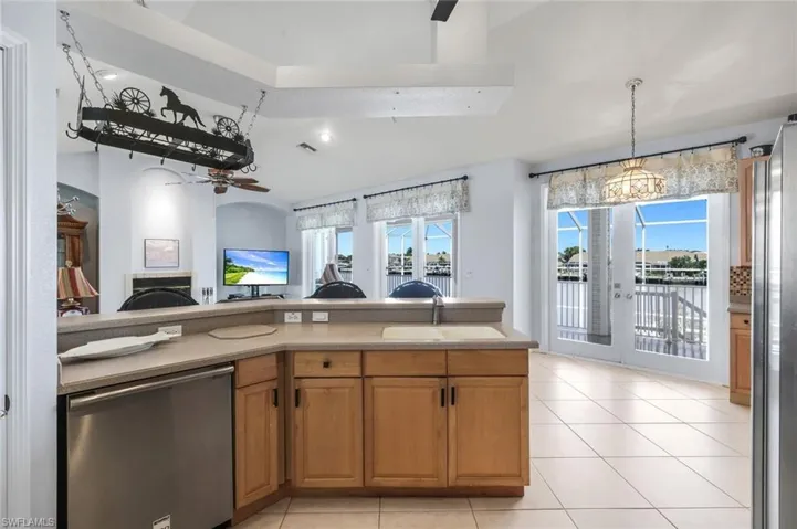 Kitchen featuring stainless steel appliances, wood finish cabinetry, open floor plan, ceiling fan, and a fireplace