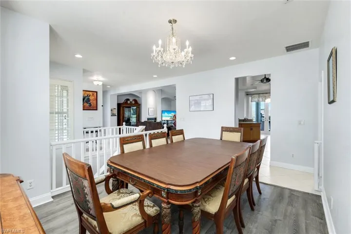 Dining space with suspended lighting, light wood-type flooring, ceiling fan, and arched walkways