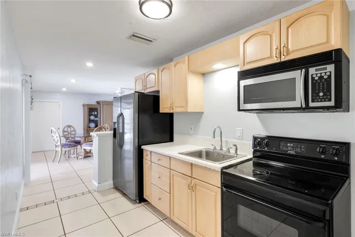 Kitchen featuring light wood finish cabinetry, stainless steel appliances, recessed lighting, light tile patterned floors, and light countertops