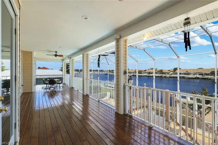 Deck featuring a ceiling fan, a water view, and glass enclosure