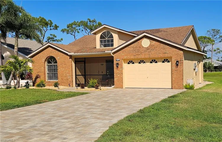 View of front facade with brick siding, a front yard, an attached garage, and decorative driveway