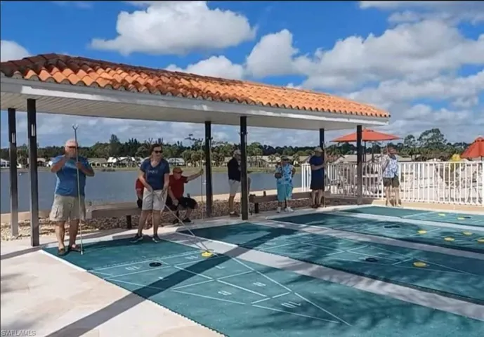 View of community with shuffleboard and fence