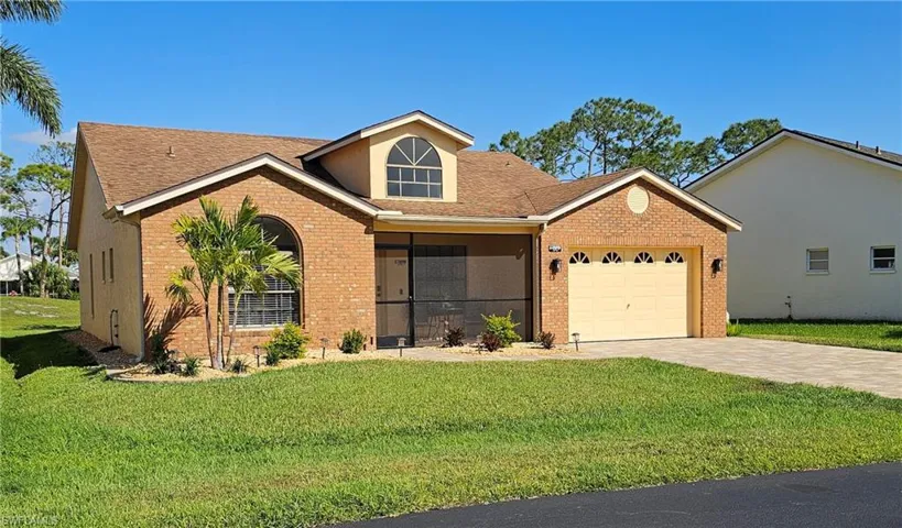 View of front of property with a front yard, a garage, brick siding, driveway, and roof with shingles