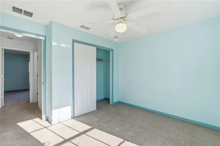 Unfurnished bedroom featuring carpet flooring, a closet, and a ceiling fan