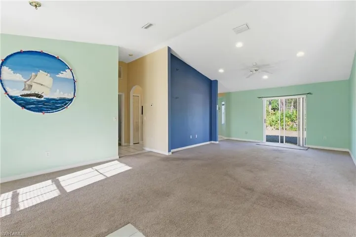 Empty room with vaulted ceiling, arched walkways, a ceiling fan, light carpet, and recessed lighting
