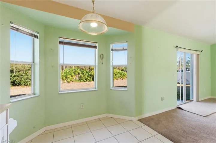 Empty room with light tile patterned flooring, healthy amount of natural light, and light carpet
