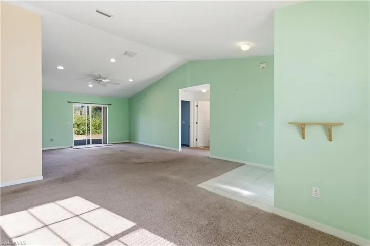 Empty room featuring light carpet, ceiling fan, and light tile patterned floors