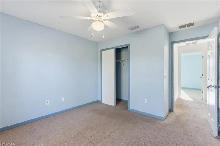 Unfurnished bedroom featuring carpet flooring, a closet, and a ceiling fan