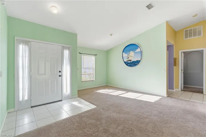 Entryway featuring light tile patterned floors, lofted ceiling, and light carpet