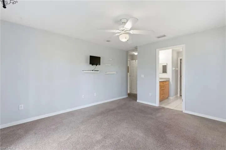 Unfurnished bedroom with light colored carpet, a ceiling fan, and ensuite bathroom