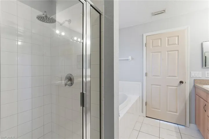 Bathroom featuring vanity, a garden tub, a stall shower, and light tile patterned flooring