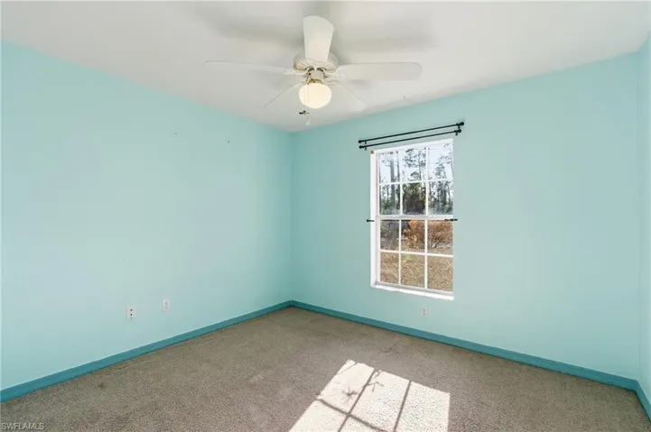 Carpeted empty room with baseboards and a ceiling fan
