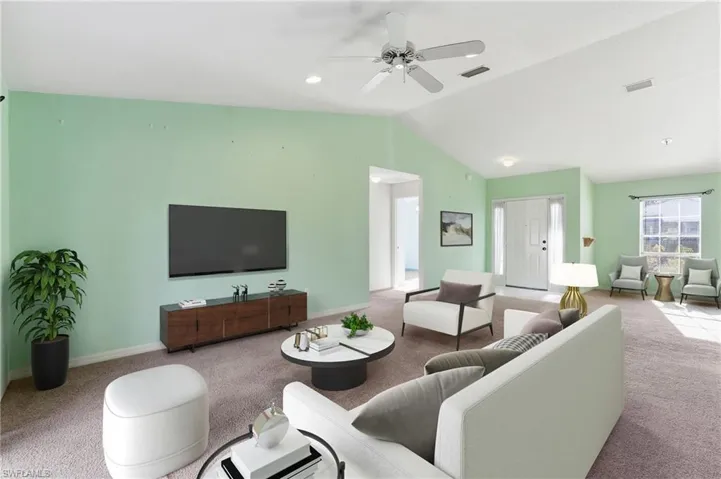 Carpeted living area with a ceiling fan and baseboards