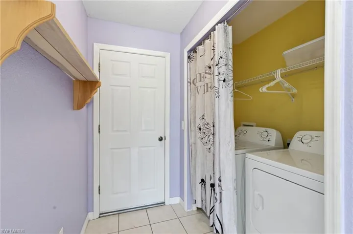 Laundry area featuring light tile patterned flooring, independent washer and dryer, and a textured ceiling
