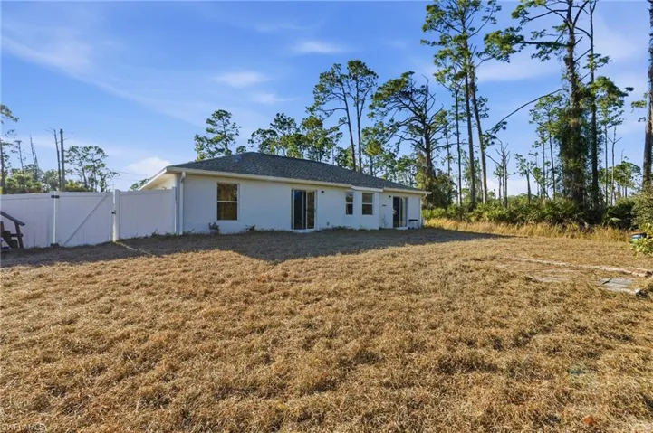 Back of property featuring a gate, stucco siding, and a yard