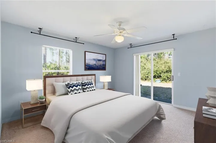Bedroom featuring access to outside, light colored carpet, multiple windows, and a ceiling fan