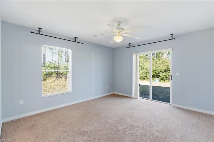 Carpeted empty room with a ceiling fan and healthy amount of natural light