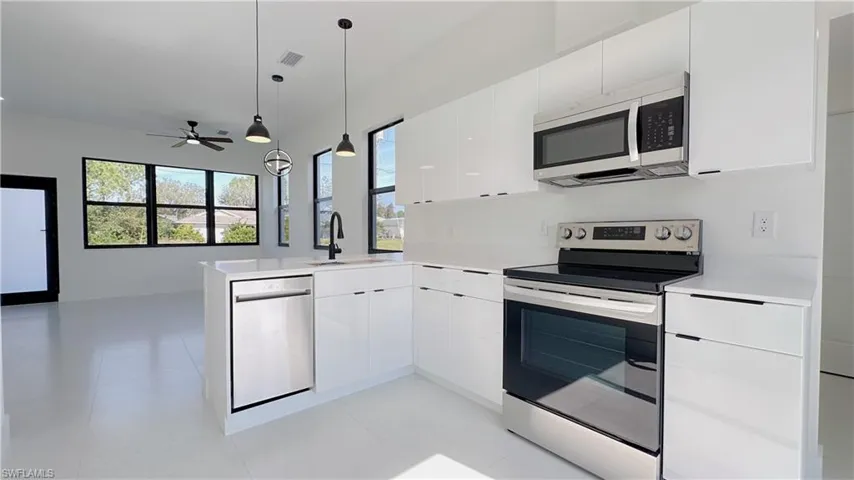 Kitchen featuring appliances with stainless steel finishes, modern cabinets, white cabinets, and a peninsula
