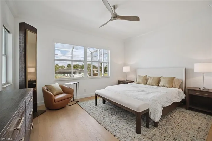 First floor bedroom with wood flooring, crown molding, and ceiling fan