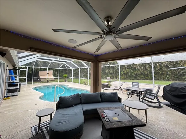 Swimming pool with a sunroom, a patio area, grilling area, and a lanai