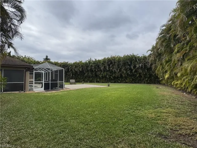 View of green lawn with glass enclosure and a sunroom