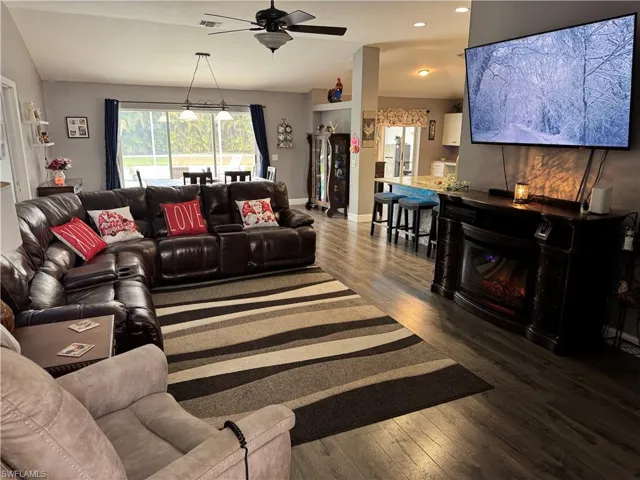 Living room featuring dark wood-style flooring, recessed lighting, ceiling fan, and lofted ceiling