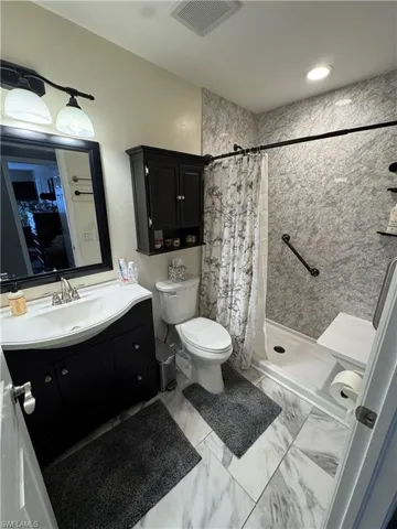 Bathroom featuring a shower stall, vanity, and light marble finish flooring