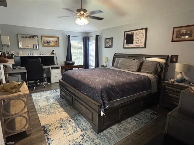 Bedroom with dark wood-type flooring, a desk, ceiling fan, and a textured ceiling