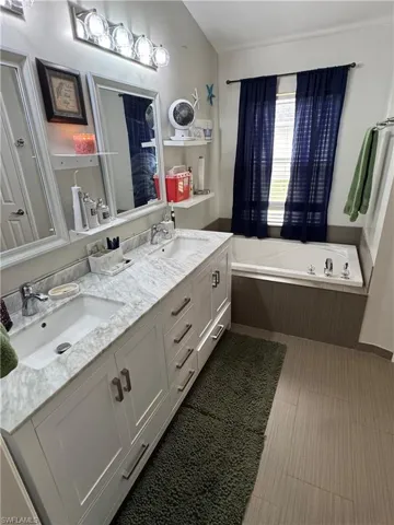 Full bath featuring double vanity, a bath, and lofted ceiling