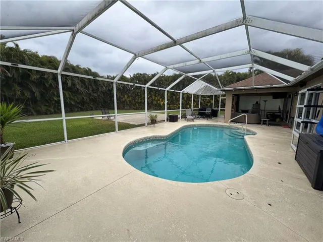 Swimming pool featuring a sunroom, a lanai, a yard, and a patio area