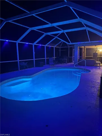 Pool at twilight with an outdoor pool, a lanai, a sunroom, and a patio