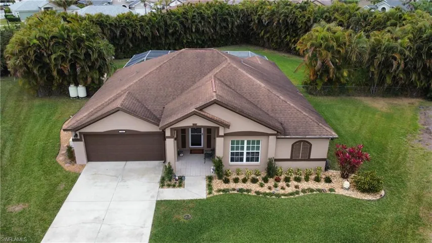 Single story home featuring stucco siding, a lanai, a front yard, roof with shingles, and driveway
