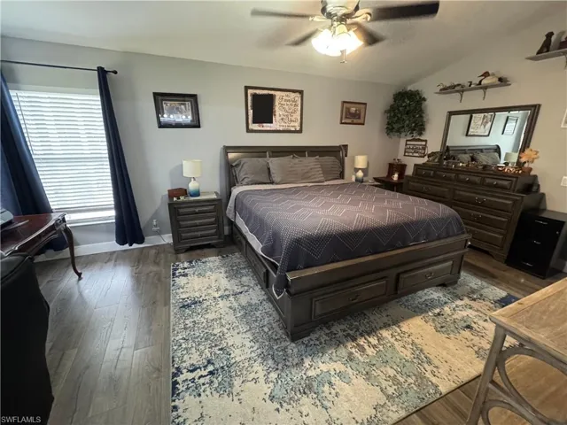 Bedroom with wood finished floors, ceiling fan, and vaulted ceiling
