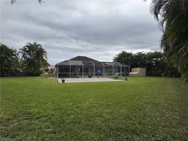 Back of property with glass enclosure, a sunroom, a yard, and a patio