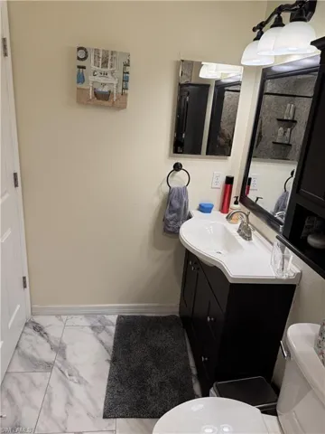 Half bath featuring vanity and light marble finish floors