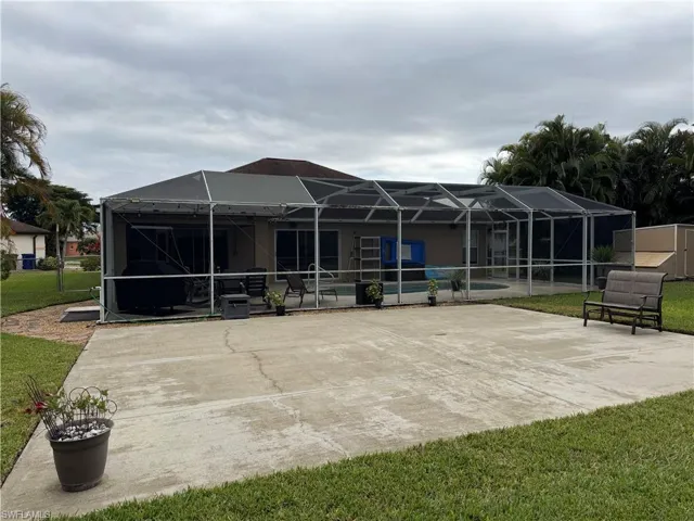 Rear view of property with glass enclosure, a patio, a sunroom, a lawn, and a storage shed