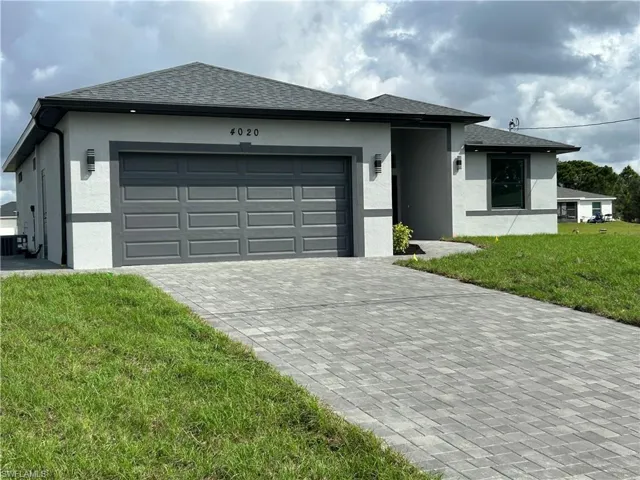View of front of house with a front lawn, stucco siding, decorative driveway, and a shingled roof