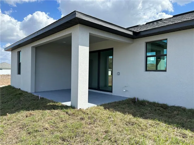 Back of house featuring a yard, a patio, and stucco siding
