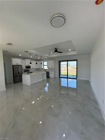 Unfurnished living room with a raised ceiling, ceiling fan, and recessed lighting