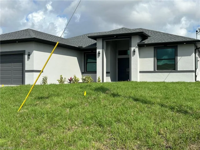 View of front of property featuring a garage, roof with shingles, stucco siding, and a front yard