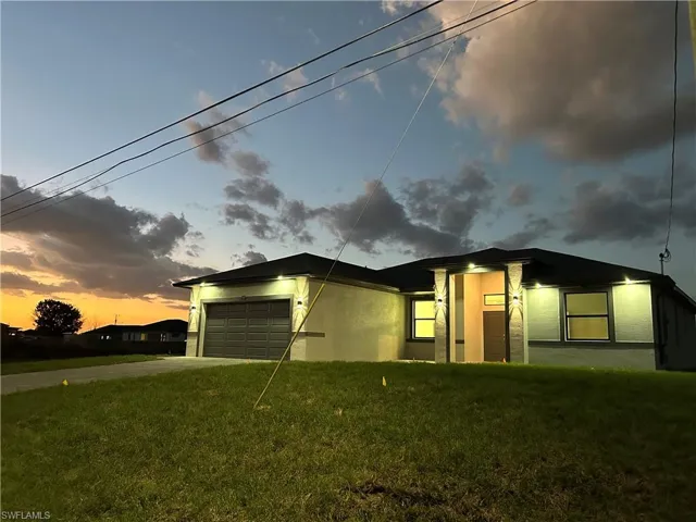 View of front of home with a front yard, an attached garage, concrete driveway, and stucco siding