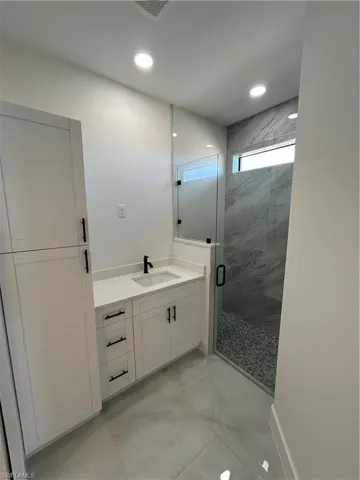 Full bath with vanity, a marble finish shower, and recessed lighting