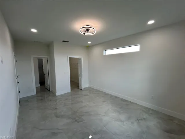 Unfurnished bedroom featuring a walk in closet, recessed lighting, and finished concrete flooring