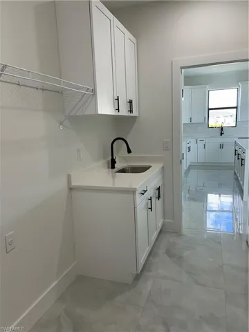 Laundry area featuring light marble finish flooring and cabinet space