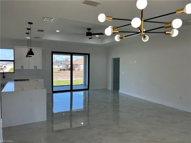 Spare room featuring a tray ceiling, ceiling fan, and hanging lights