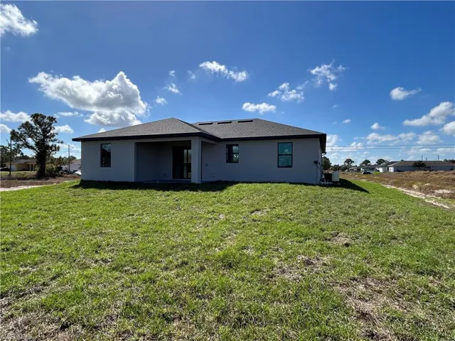 Back of property with stucco siding, a yard, and a patio