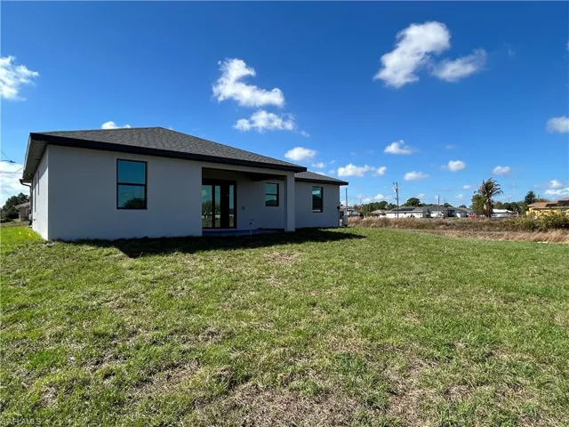 Back of property with stucco siding, a lawn, and a patio area